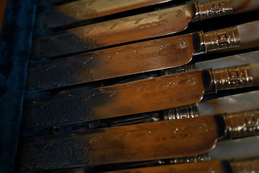 A cased set of twelve pairs of mother of pearl handled plated dessert eaters and a quantity of assorted plated items including a toastrack, a pair of mounted glass condiments, crumb scoop and miscellaneous flatware.